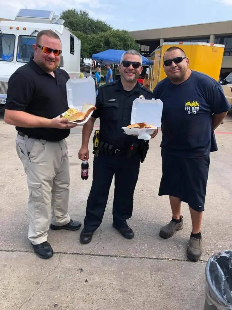 Angel Espinoza with police officers holding barbecue plates