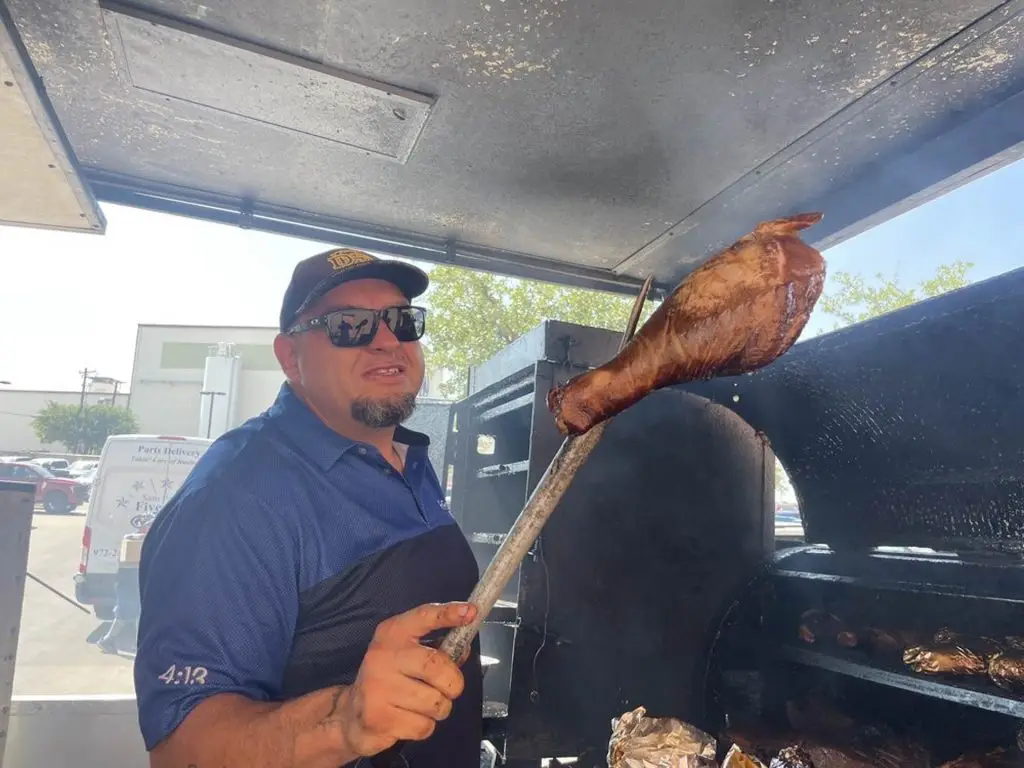 Angel Espinoza holding a smoked turkey leg at the smoker